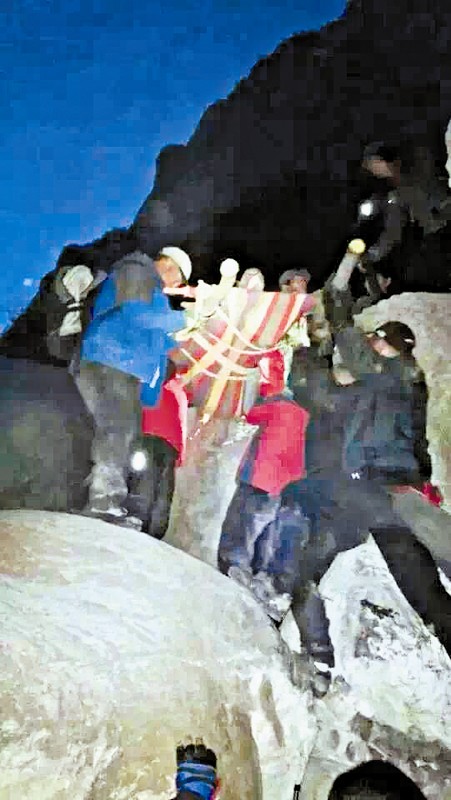 救援隊員用自制的簡易擔架抬傷者。